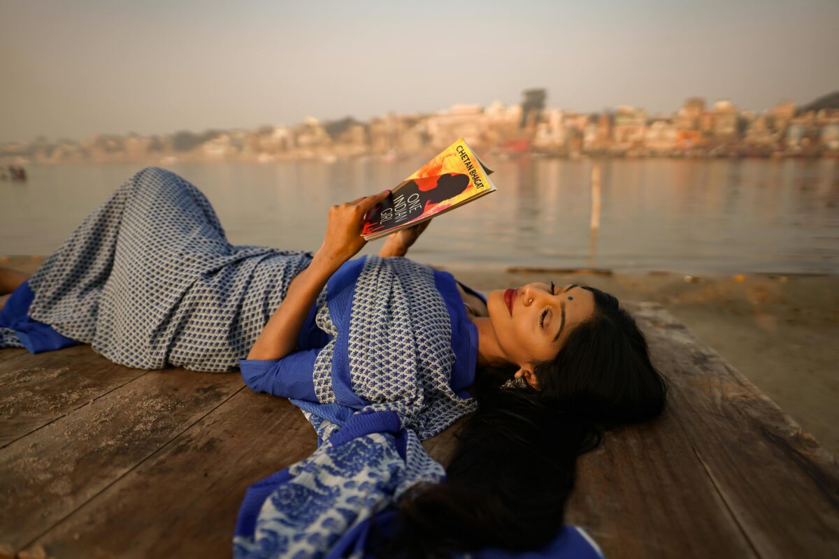 Traveler in traditional Indian wear looking out over Ganges River at sunrise