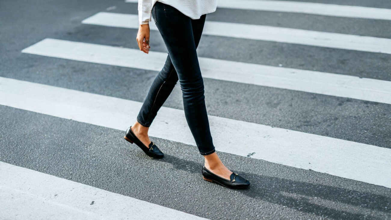 woman walking crosswalk in black derby flats